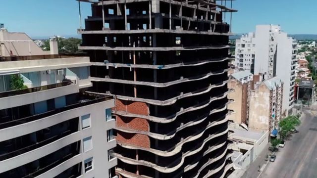 Una mujer lanza piedras desde el séptimo piso de a construcción paralizada.