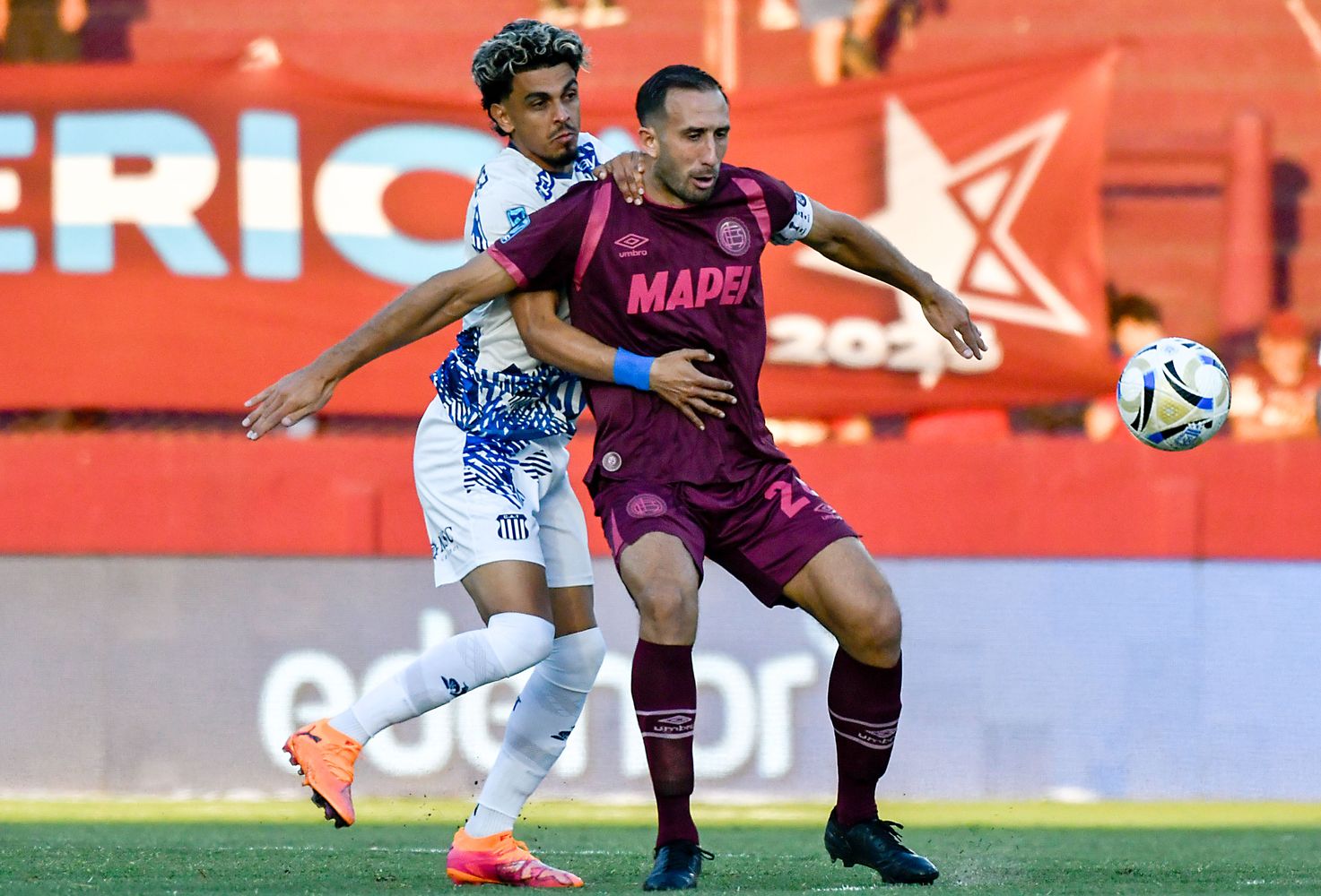 Ronaldo Martínez, el goleador que necesita Talleres, apura al "Cali" Izquierdoz en el partido con Lanús.
