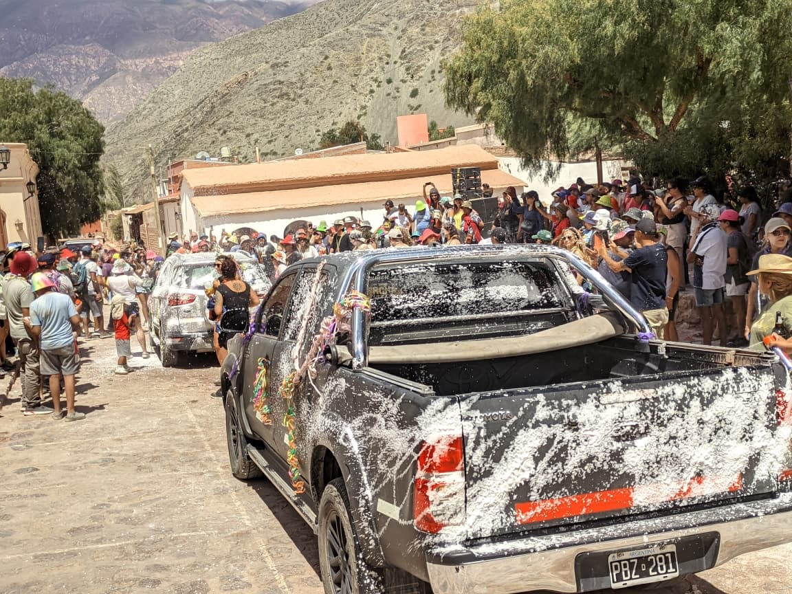 En Purmamarca, la caravana de vehículos que llega al pueblo es recibida por los carnavaleros que dan la bienvenida a los viajeros con talco, espuma y toda la alegría del festejo.