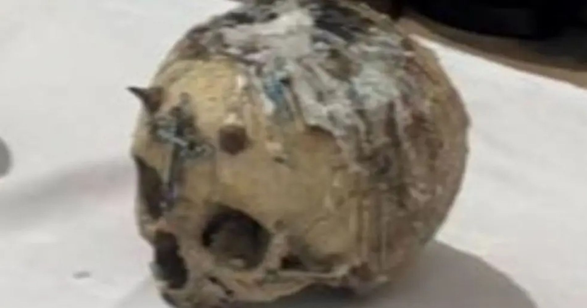 Un cráneo estaba cubierto con cera de vela blanca y negra y tenía un crucifijo metálico adherido en el medio de los ojos
