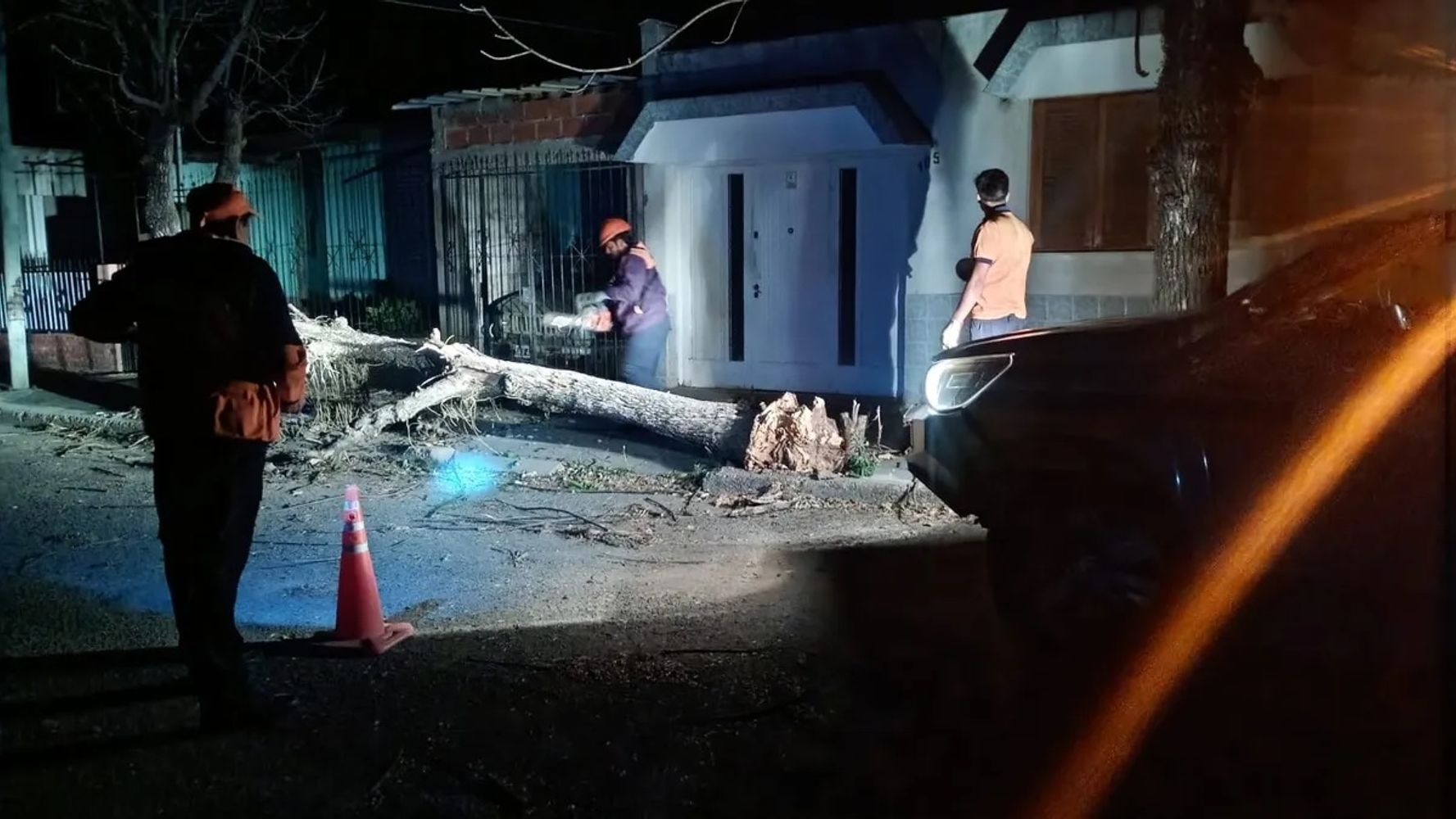 Alumbrados por las luces de sus vehículos, operarios de cuadrillas de emergencias trabajando de noche, para liberar el cableado eléctrico que arrastró un árbol en su caída, el viernes en la capital jujeña.