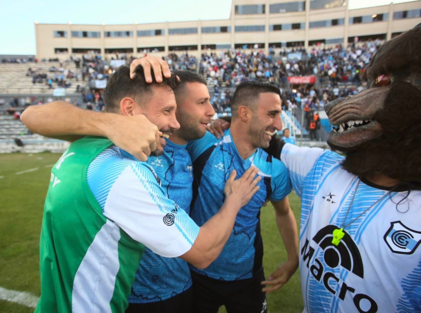La mascota de Gimnasia de Jujuy felicita al entrenador Hernán Pellerano, en la celebración del triunfo. Con 41 unidades en total, el equipo jujeño permanecerá en la cima de su zona una fecha más, sin que ninguno de sus contrincantes pueda acercársele.