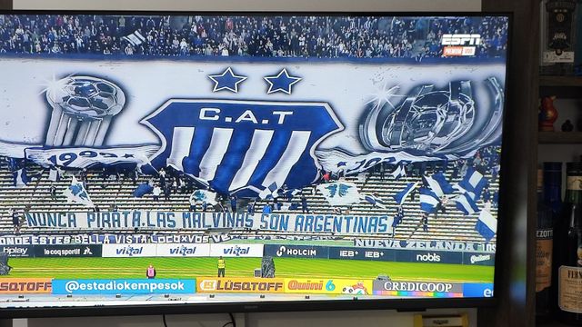 Los hinchas de Talleres y las banderas desplegadas. Una, con chicana para los hinchas de Belgrano...