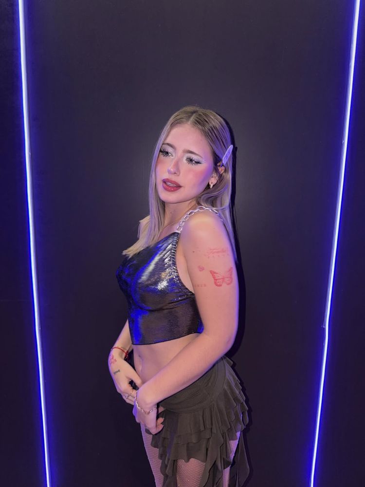 Top metalizado con bretel de cadena, minifalda con volados y maquillaje de fantasía: el look dosmilero de Coti Romero