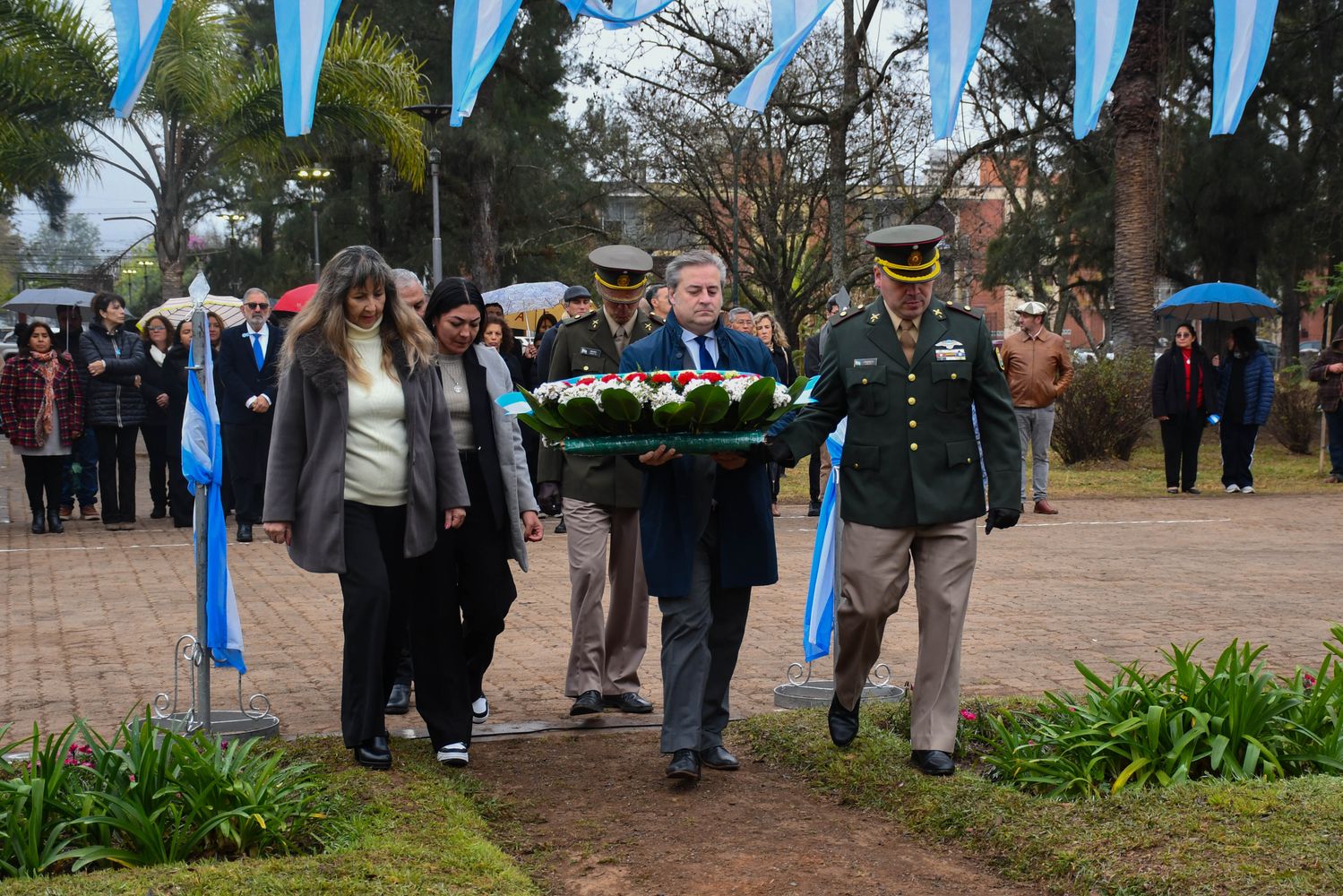 El presidente del Concejo Deliberante capitalino, Gastón Millón, acompañado por las concejales Ontiveros y Carabajal, junto a jefes castrenses, al momento de colocar una ofrenda floral ante el monumento que recuerda al Padre de la Patria.