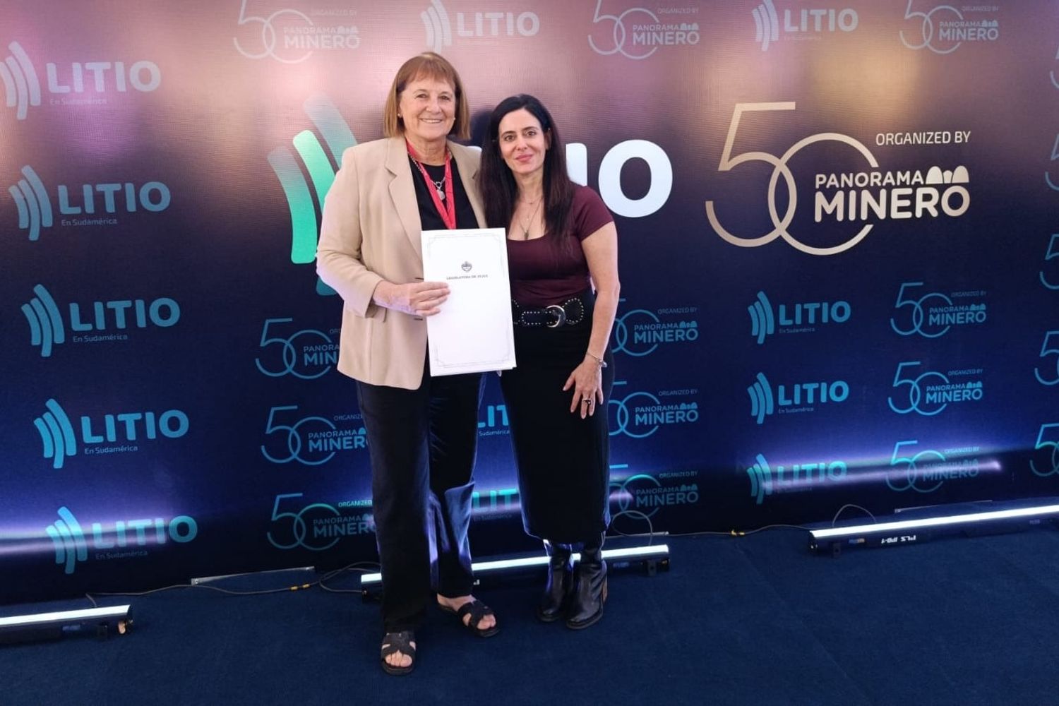 La diputada Alejandra Mollón (izq.) entregó a la directora institucional de la revista Panorama Minero, Mercedes Rodríguez, la declaración de interés legislativo otorgada al Seminario Internacional del Litio que se desarrolla en Jujuy.
