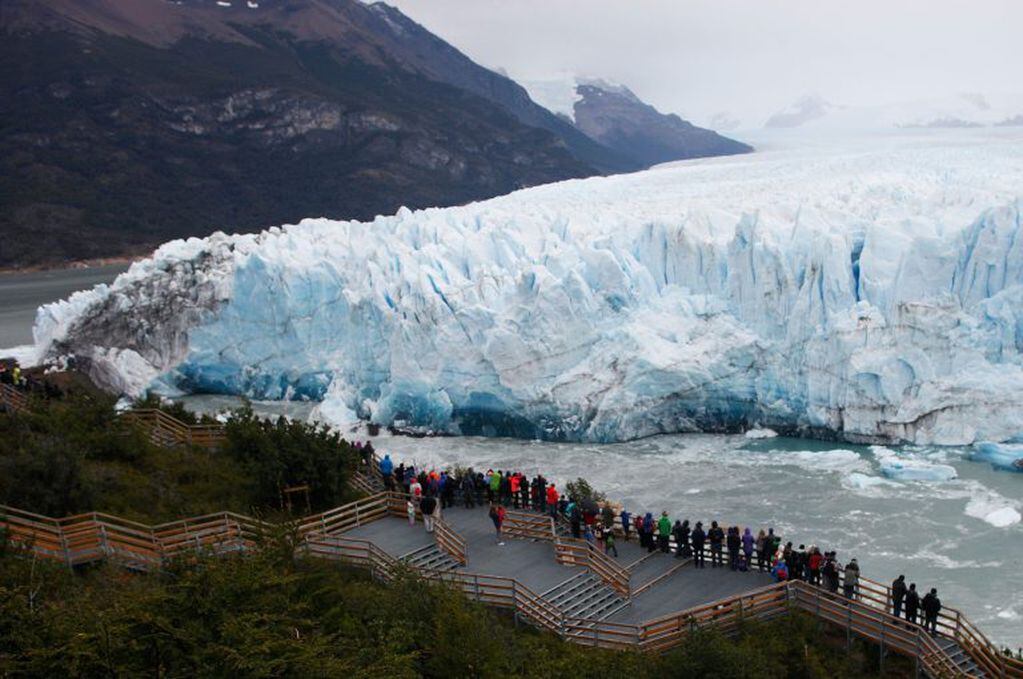 Tourists watch the Perito Moreno Glacier, at Los Glaciares National Park, near El Calafate in the Argentine province of Santa Cruz, on March 10, 2018.
An arch of ice formed at the tip of the Perito Moreno, between the glacier and the shore of Argentino lake, started collapsing into the water on Saturday, a natural display that happens just once every several years. Such arches form roughly every two to four years, when the glacier forms a dam of ice that cuts off the flow of water around it into the lake -- until the water breaks through, opening up a steadily wider tunnel that eventually becomes a narrow arch... and then collapses. / AFP PHOTO / Walter Diaz santa cruz  imponente ruptura del arco hielo arco de hielo del glaciar Perito Moreno se cayo durante la noche vista vistas del proceso de ruptura
