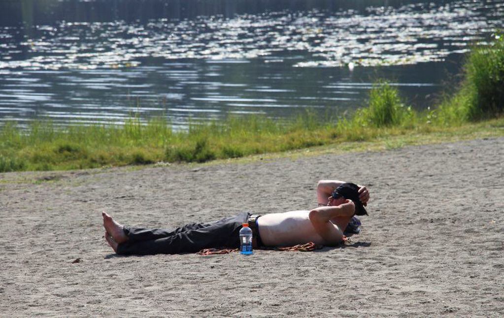 Con temperaturas de 32°C, un hombre toma sol a la orilla del lago. Foto: AP Mark Thiessen.