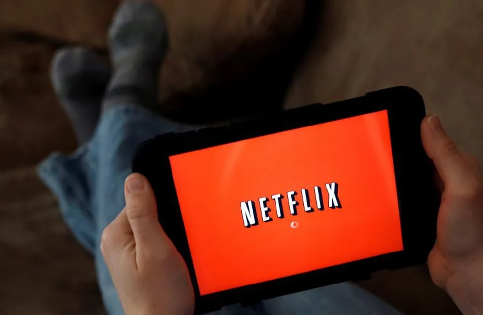 FILE - In this Friday, Jan. 17, 2014, file photo, a person displays Netflix on a tablet in North Andover, Mass. Netflix subscribers can now download shows and movies to watch later when theyu2019re not online, like during a flight or car. The download option 