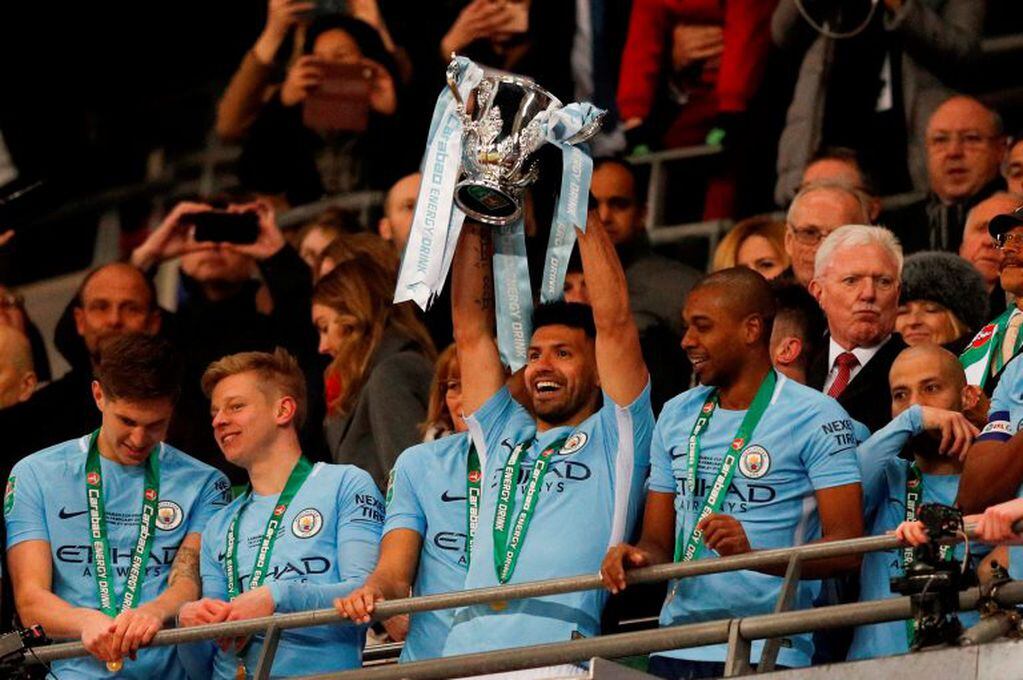 Manchester City's Argentinian striker Sergio Aguero lifts the trophy as Manchester city players celebrate their victory in the English League Cup final football match between Manchester City and Arsenal at Wembley stadium in north London on February 25, 2018.
Manchester City won the first trophy of the Guardiola era on Sunday, thumping a disappointing Arsenal 3-0 in the League Cup final at Wembley. / AFP PHOTO / Adrian DENNIS / RESTRICTED TO EDITORIAL USE. No use with unauthorized audio, video, data, fixture lists, club/league logos or 'live' services. Online in-match use limited to 75 images, no video emulation. No use in betting, games or single club/league/player publications.  /