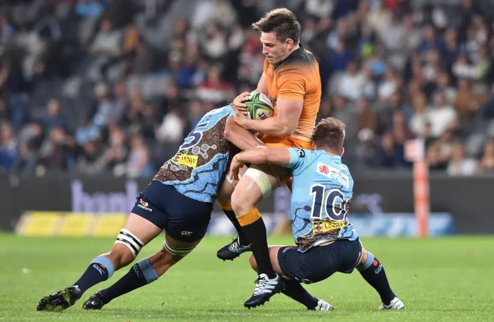 Jaguares' Tomas Lezana (C) is tackled by Waratahs players Rob Simmons (L) and Bernard Foley (R) during the Super Rugby match between Australia's NSW Waratahs and Argentina's Jaguares at BankWest Stadium in Sydney on May 25, 2019. (Photo by PETER PARKS / AFP) / IMAGE RESTRICTED TO EDITORIAL USE - STRICTLY NO COMMERCIAL USE