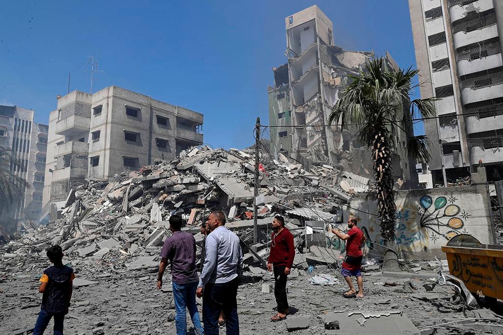 Unas personas observan los escombros del edificio residencial Yazegi destruido por un bombardeo de Israel en Gaza.