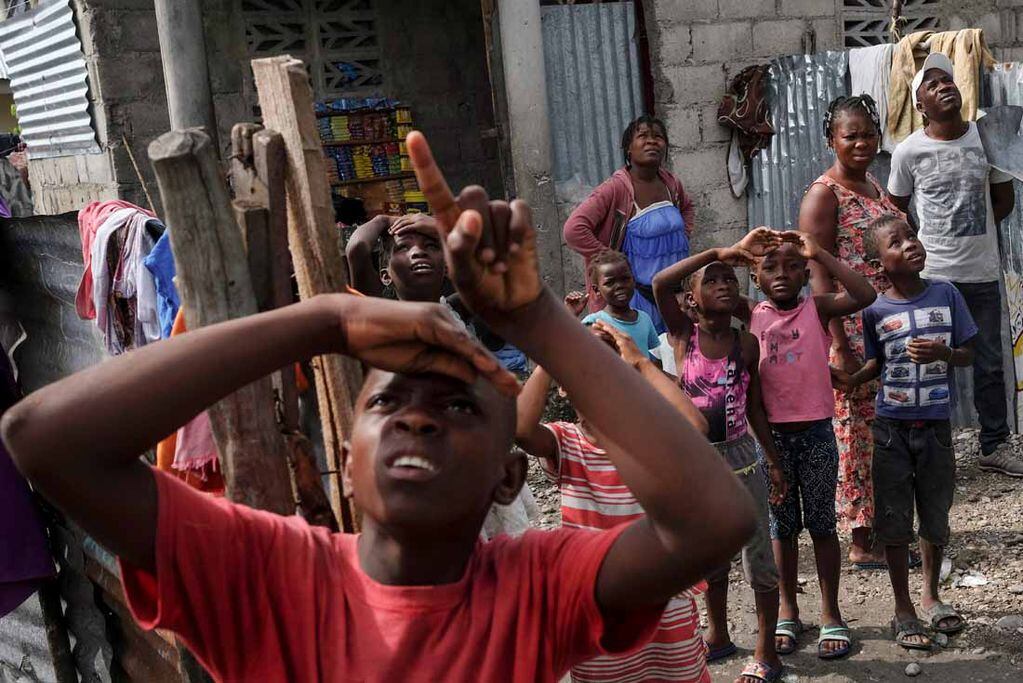 Un niño señala un helicóptero que se acerca y trae ayuda para los sobrevivientes del terremoto en un vecindario cerca del aeropuerto en Les Cayes, Haití. (AP/Matias Delacroix)