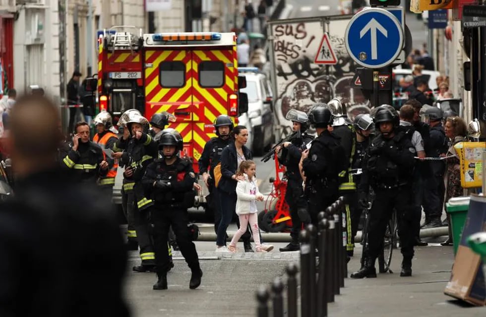 Una mujer y una niña (c) son evacuadas por las fuerzas policiales durante una supuesta toma de rehenes en la Rue des Petites Ecuries, en París (Francia).