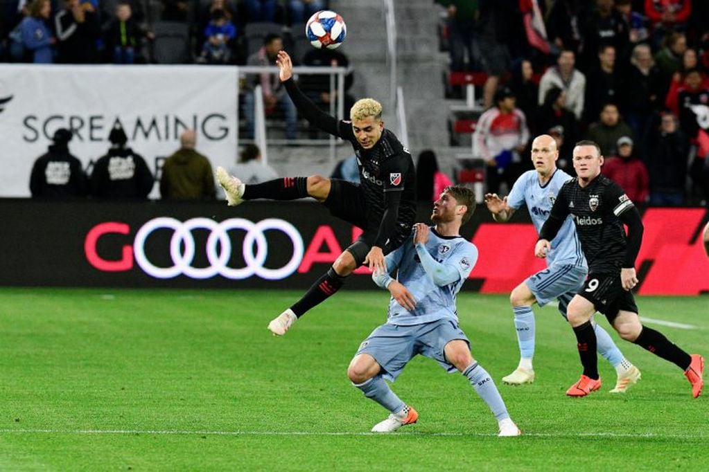 May 12, 2019; Washington, D.C., USA; D.C. United midfielder Lucas Rodriguez (11) heads the ball as Sporting Kansas City midfielder Nicolas Hasler (14) defends during the first half at Audi Field. Mandatory Credit: Tommy Gilligan-USA TODAY Sports