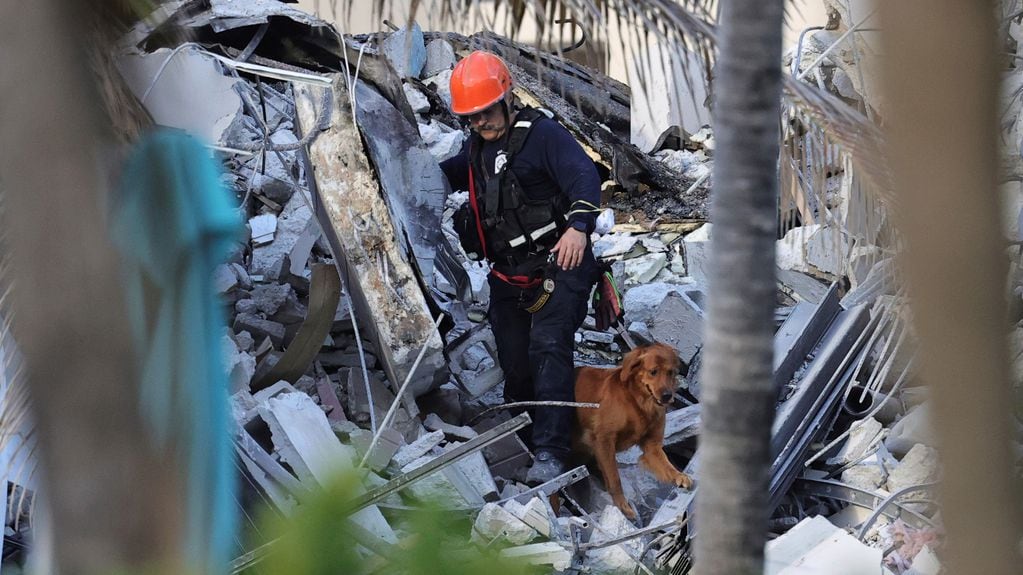 Bomberos y rescatistas buscan personas desaparecidas bajo los escombros, tras el derrumbe parcial de un edificio en Surfside, Miami.