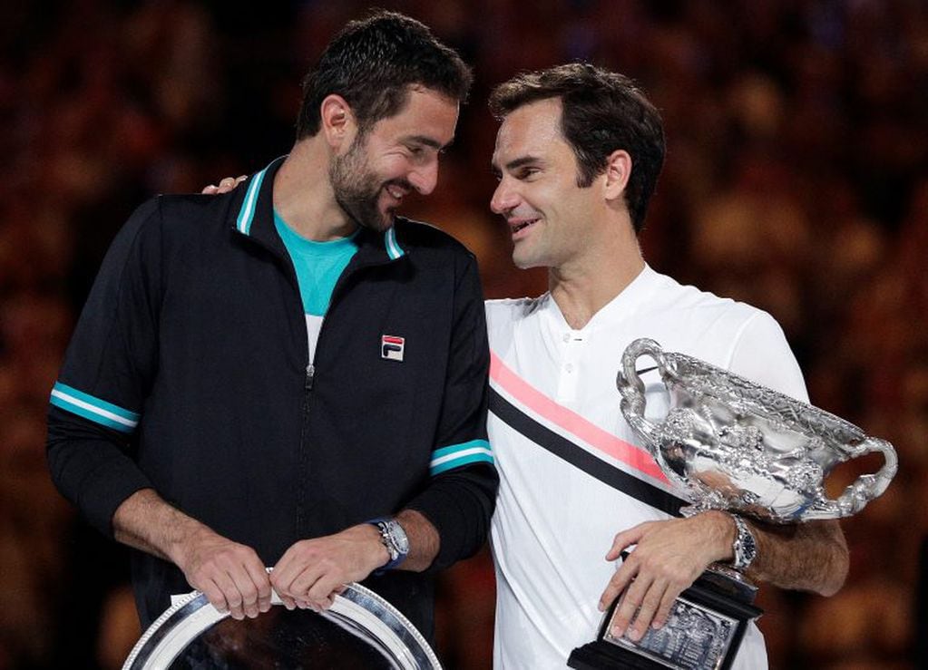 Switzerland's Roger Federer, right, holds his winner's trophy as he talks with Croatia's Marin Cilic following the men's singles final at the Australian Open tennis championships in Melbourne, Australia, Sunday, Jan. 28, 2018. (AP Photo/Dita Alangkara)