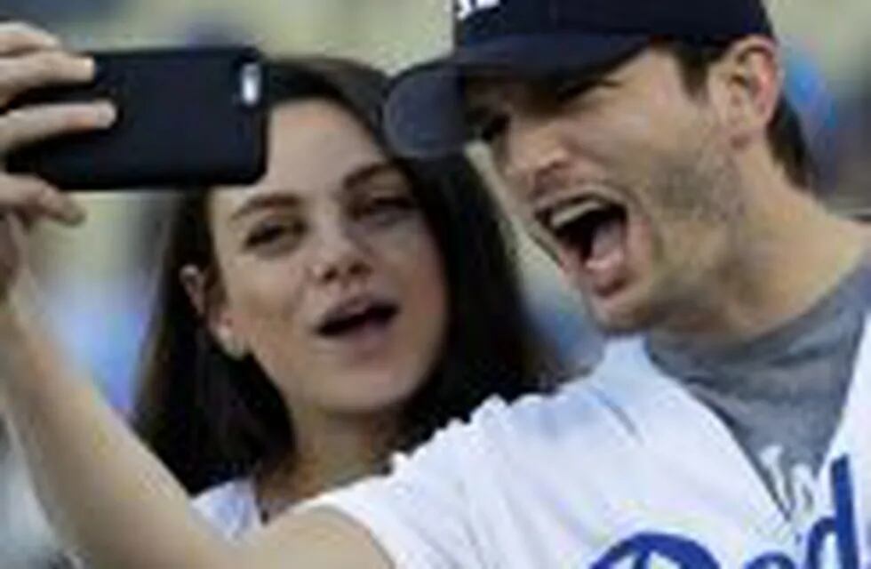 FILE- In this Oct. 19, 2016, file photo, Ashton Kutcher and wife Mila Kunis take a selfie before Game 4 of the National League baseball championship series between the Chicago Cubs and the Los Angeles Dodgers in Los Angeles. Kutcher and Kunis have offered