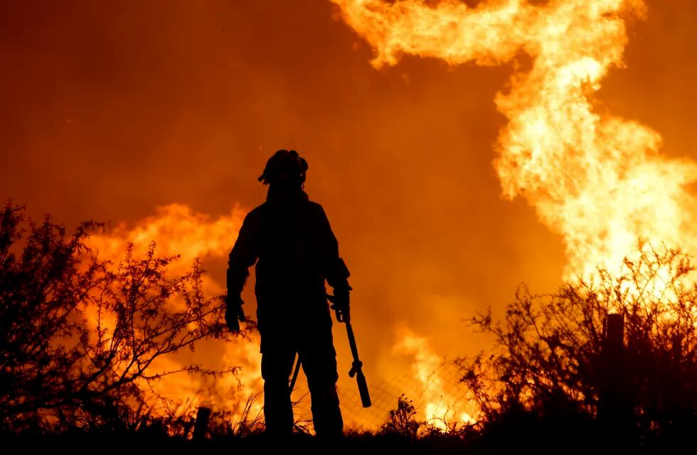 La silueta de un bombero se recorta sobre las llamas que arrasan un bosque en un incendio a las afueras de Villa Carlos Paz, Argentina, el 10 de octubre de 2023. (AP Foto/Nicolás Aguilera)