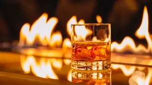 side view of glass of whiskey with ice on a background of a burning flame