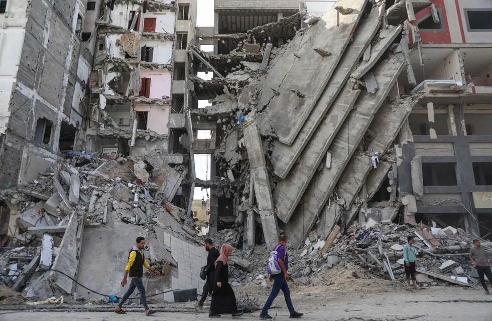 Palestinos caminan frente a edificios impactados por ataques israelíes en Ciudad de Gaza.