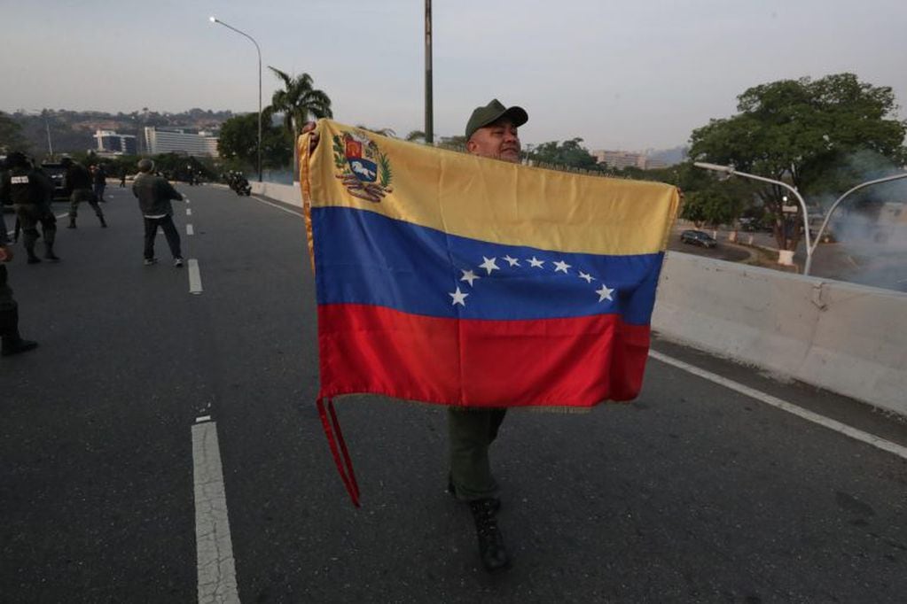 Un militar despliega una bandera en la base de La Carlota, al este de Caracas (Foto: Rayner Peña/EFE)