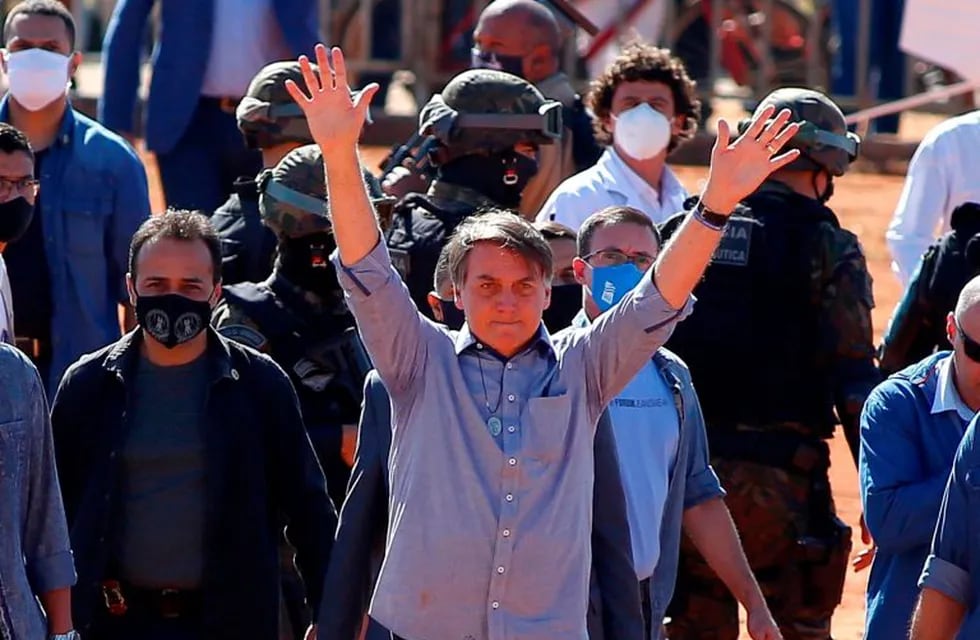Brazilian President Jair Bolsonaro (C) waves to supporters during the inauguration of a field hospital in Aguas Lindas, in the State of Goiais, Brazil, on 05 June 2020, amid the Covid-19 coronavirus pandemic. (Photo by Sergio LIMA / AFP)