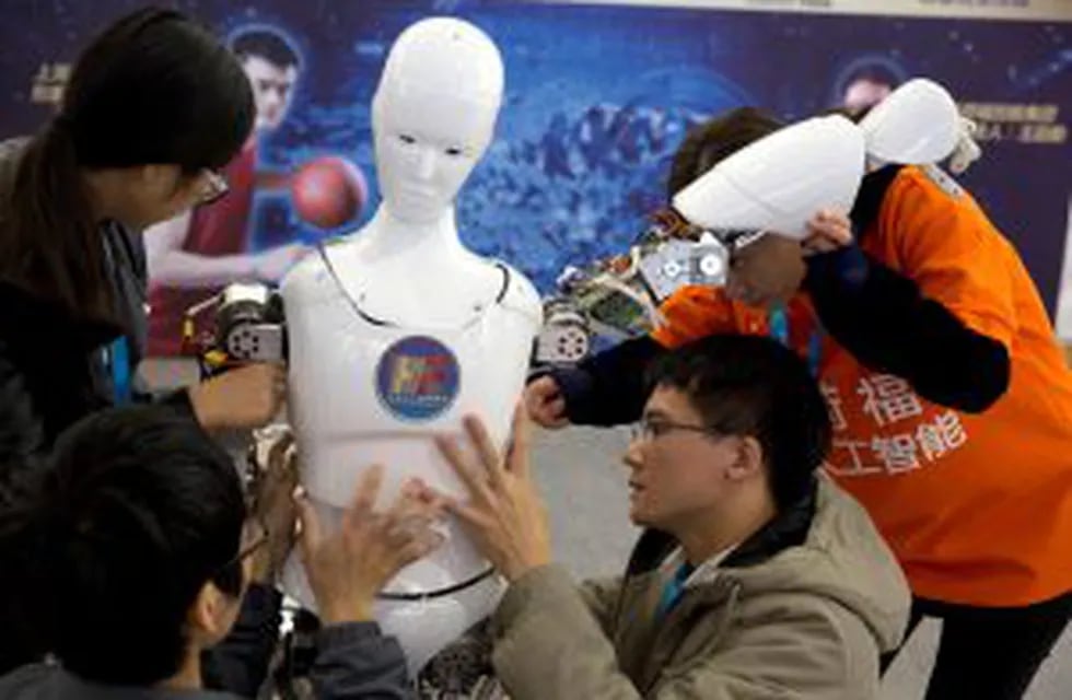 In this Friday, Oct. 21, 2016 photo, Chinese students work on the Ares, a humanoid bipedal robot designed by them with fundings from a Shanghai investment company, displayed during the World Robot Conference in Beijing. China is showcasing its burgeoning robot industry as it seeks to promote use of more advanced technologies in Chinese factories and create high-end products that redefine the meaning of u201cMade in China.u201d The Ares is a human-sized robot they designed with exposed metal arms and hands and a wide range of uses in mind, from the military to performing basic tasks in a home. (AP Photo/Ng Han Guan) china beijing  china exhibicion sobre robotica en beijing conferencia mundial sobre robots