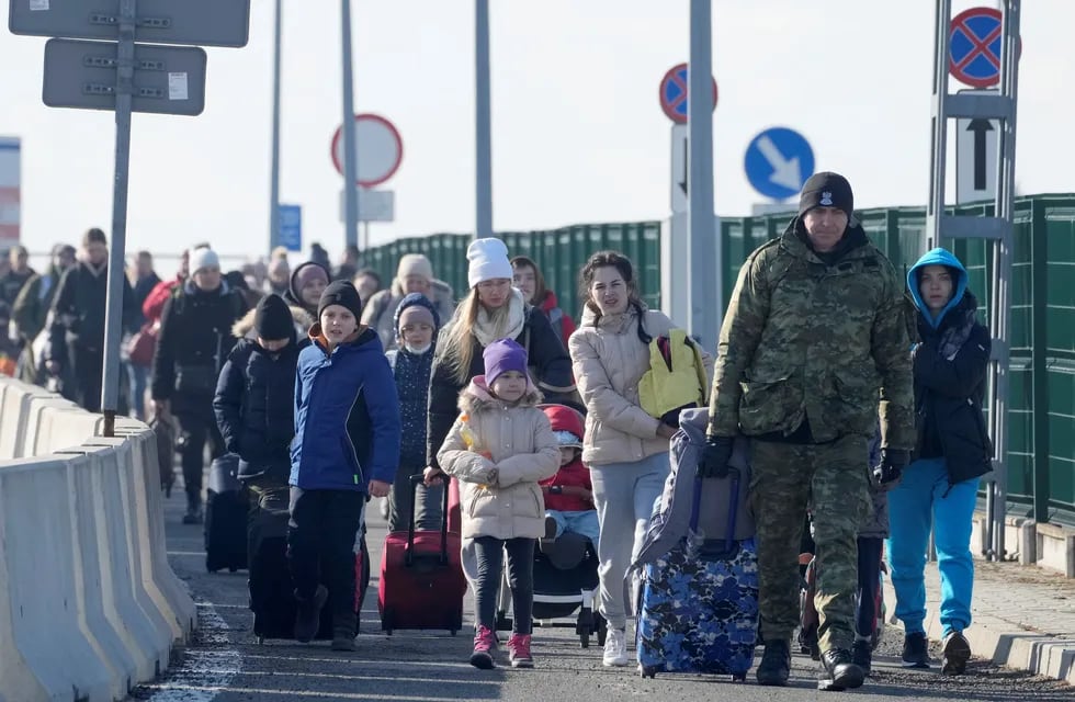 Cruce de Korczowa. Un guardia fronterizo polaco ayuda a los refugiados de Ucrania a llegar a Polonia (AP).