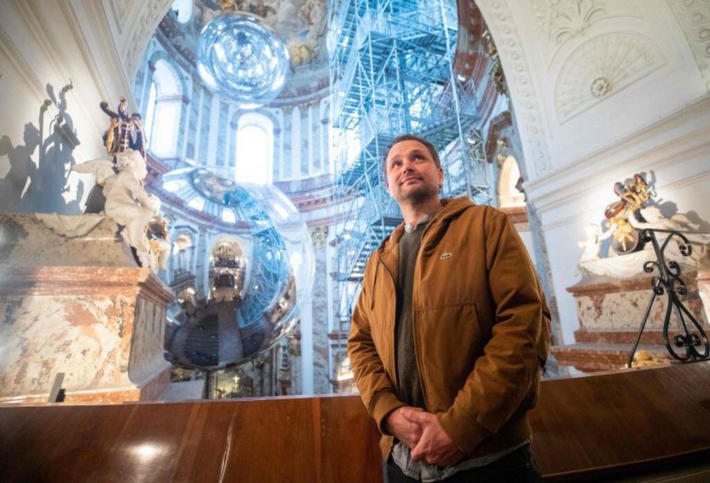 El artista argentino Tomás Saraceno posa frente a su obra "Aerocene" en exhibición en la iglesia Karlskirche en Viena, Austria, el 13 de noviembre de 2018. La instalación, que formaba parte del programa "Artes contemporáneas Karlskirche", consta de dos esculturas gigantes en forma de bola instaladas en la cúpula de la iglesia barroca. (Photo by GEORG HOCHMUTH / APA / AFP)