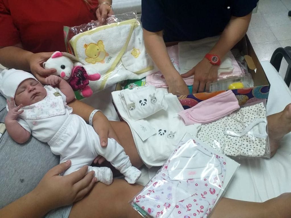Juana en los brazos de su mamá Camila y los regalos que recibió de la Cooperadora del hospital. Gentileza