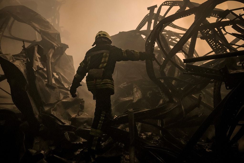Un bombero ucraniano camina por los restos destruidos de un galpón de productos alimenticios  que fue destruido por por los bombardeos rusos cerca de Kiev. (AP Photo/Vadim Ghirda)