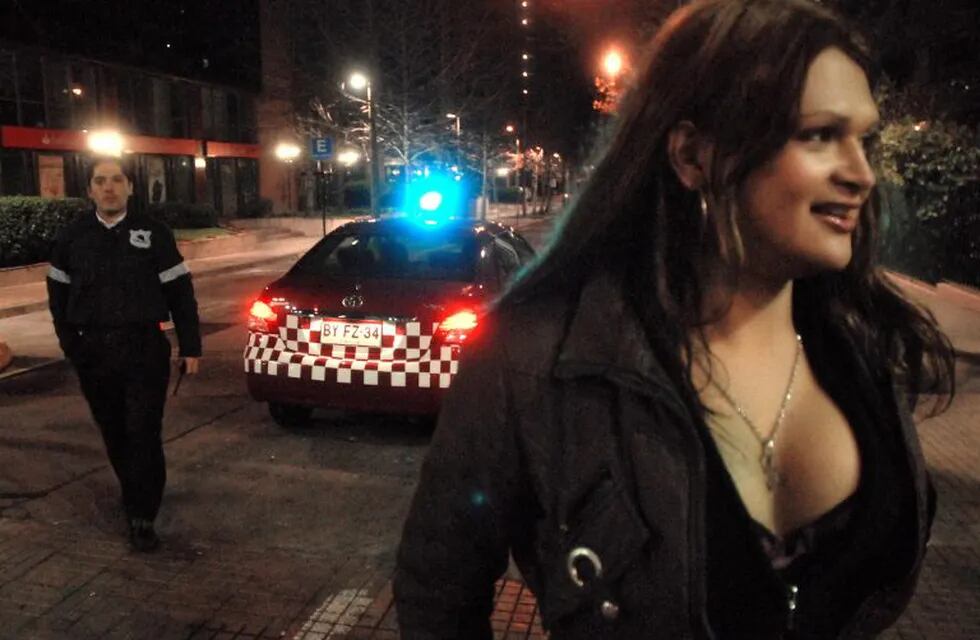 A police officer approaches Chilean transvestite prostitute, known as Katia (R), as he waits for clients on the streets of Santiago on October 13, 2009. Prostitution among adult men is legal in Chile and is practiced mainly indoors, in residential buildings. Transvestites in Chile are gathered in a movement called \
