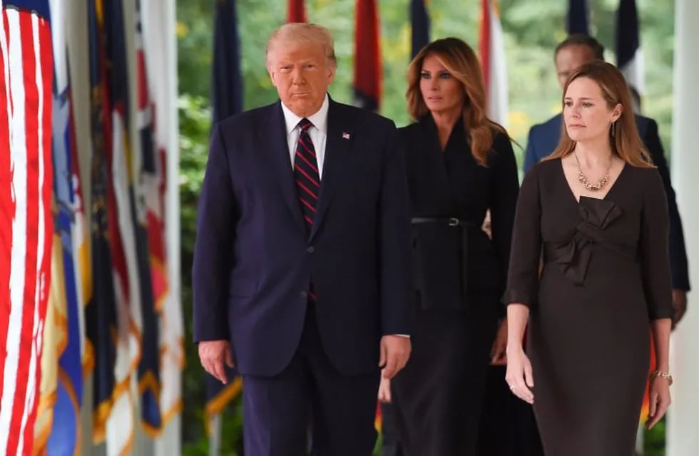 US President Donald Trump (L) and Judge Amy Coney Barrett (R), with US First Lady Melania Trump (C), arrive at the Rose Garden of the White House in Washington, DC, on September 26, 2020. - Judge Amy Coney Barrett, who was nominated Saturday to the US Supreme Court, is a darling of conservatives for her religious views but detractors warn her confirmation would shift the nation's top court firmly to the right. (Photo by Olivier DOULIERY / AFP)