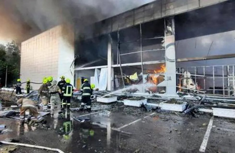 Los bomberos intentando apagar las llamas tras el ataque al centro comercial de Kremenchuk.