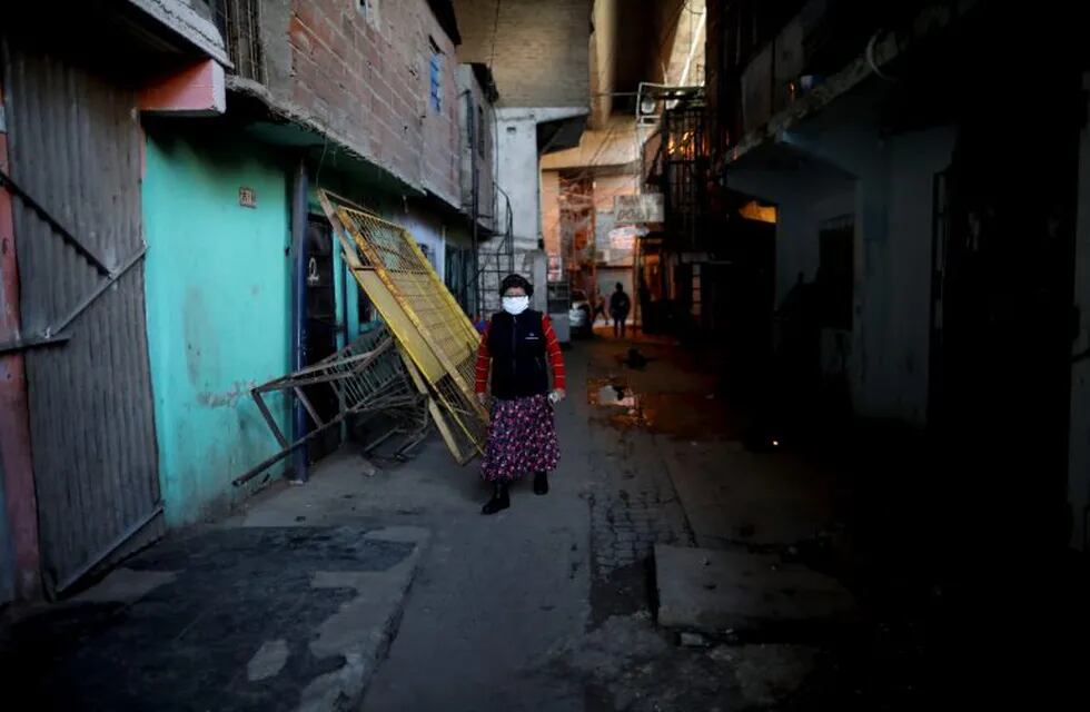 A woman walks in the Villa 31 slum during a government-ordered shutdown, in Buenos Aires, Argentina, Friday, May 1, 2020. According to official data, the number of confirmed cases of COVID-19 in the city's slum have increased in the past week, putting authorities on high alert. (AP Photo/Natacha Pisarenko)
