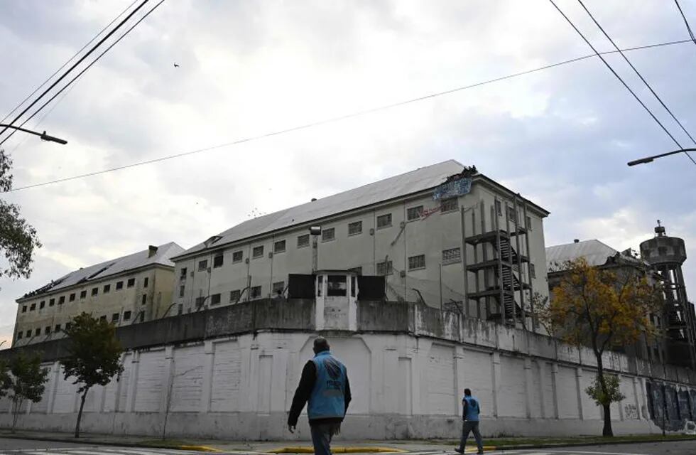 Police officers walk outside Villa Devoto prison as inmates appear from a hole on the destroyed roof of the prison during a riot in demand of preventive measures against the spread of COVID-19 after a case of the novel coronavirus was confirmed inside the facility, in Buenos Aires on April 24, 2020. (Photo by Juan MABROMATA / AFP)