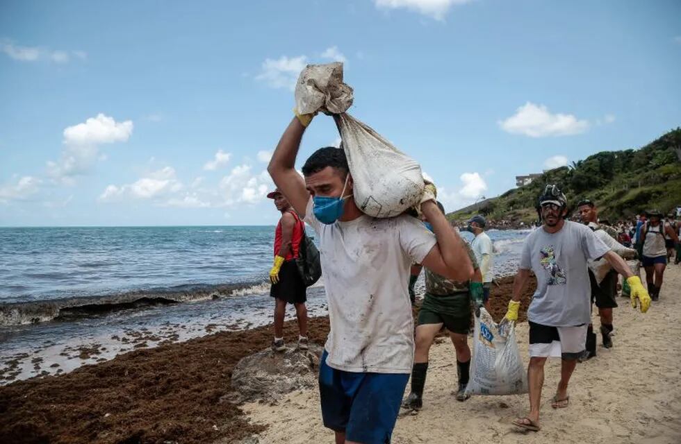 Soldados del Ejército brasileño y voluntarios retiran el petroleo derramado en la playa de Itapuama este martes en el municipio de Cabo de Santo Agostinho en el estado de Pernambuco (Brasil). Crédito: EFE/BRENDA ALCÂNTARA.