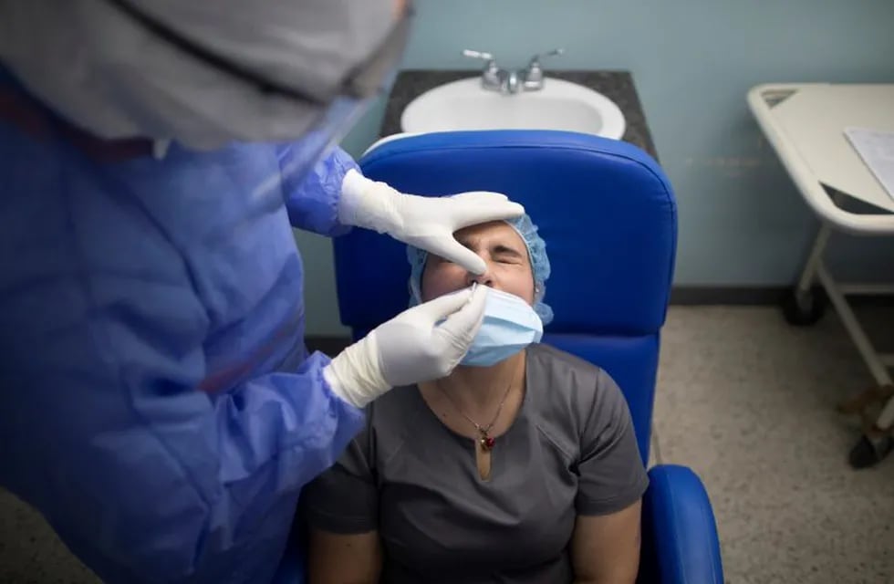 A doctor collects a swab sample from a doctor that came out positive in the COVID-19 rapid test at a comprehensive diagnosis center that set is up to attend patients with new coronavirus in Caracas, Venezuela, Thursday, Aug 27, 2020. (AP Photo/Ariana Cubillos)