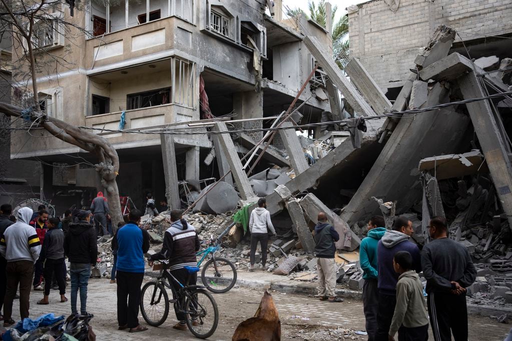 Palestinos inspeccionan los daños a edificios residenciales tras un ataque aéreo en Rafah, en el sur de la Franja de Gaza, el domingo 24 de marzo de 2024.