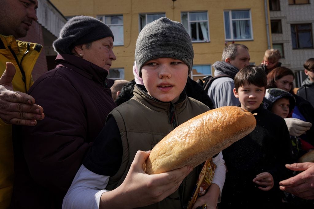 Un niño sostiene pan después de recibir ayuda humanitaria frente a una escuela en Chernihiv. (AP /Evgeniy Maloletka)
