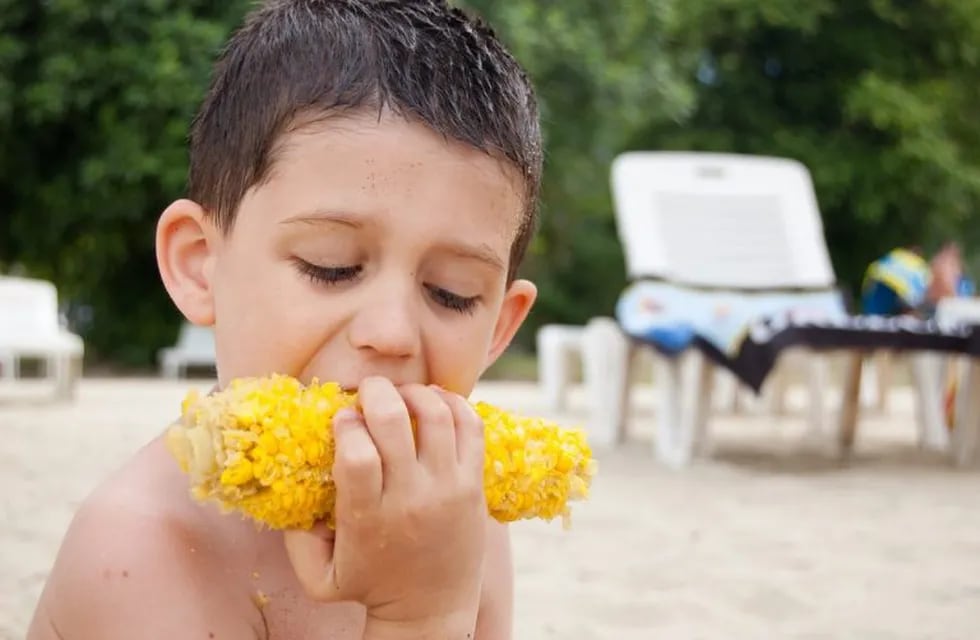 Niño comiendo choclo en la playa (PIXABAY)