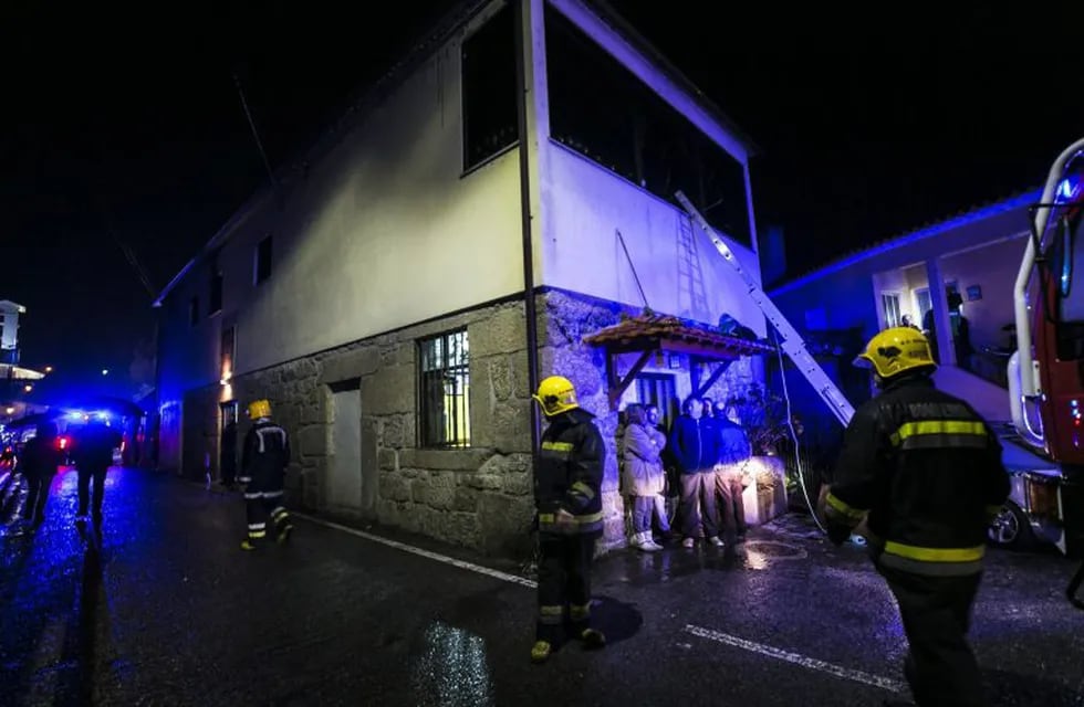 Firefighters stand outside the building of a local community centre where a fire killed eight people and injured 50 others in Vila Nova da Rainha in Tondela late on January 13, 2018. / AFP PHOTO / Maria Joao Gala