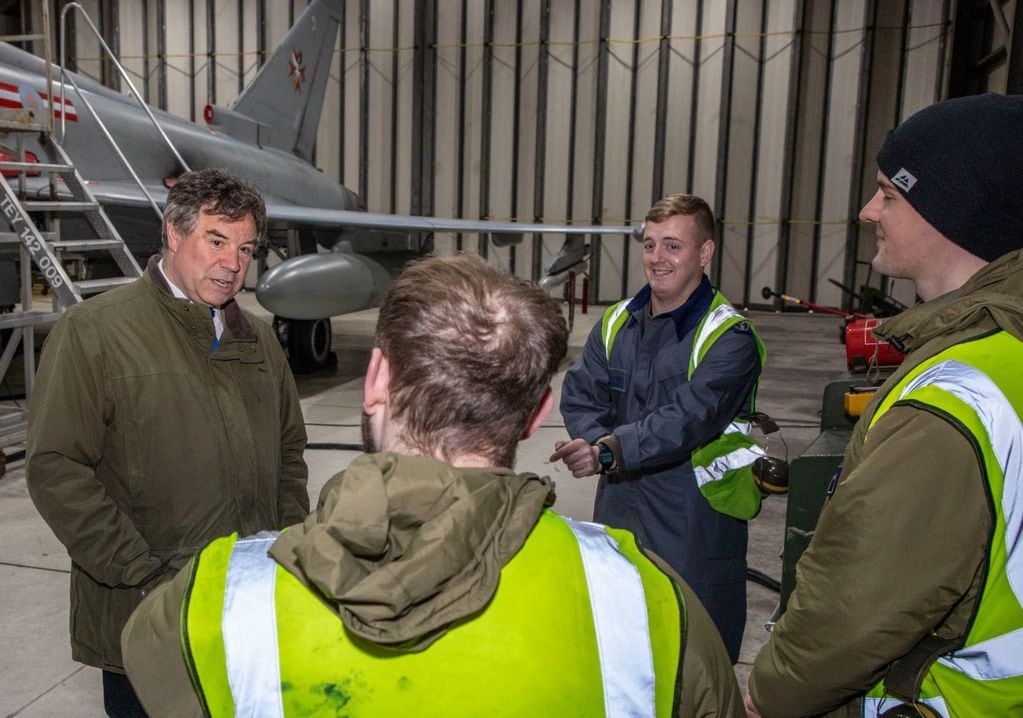 Jeremy Quin junto al cuerpo de soldados de la Real Fuerza Aérea , desplegadas en Monte Agradable, de fondo, un sistema de armas aéreas "Eurofighter Typhoon".