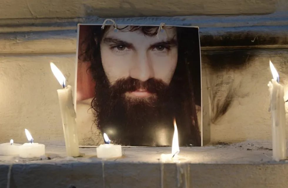 (FILES) This file photo taken on October 20, 2017 shows a portrait of Santiago Maldonado - disappeared on August 1, 2017 during a Mapuche protest in Chubut province - surrounded by candles outside the city morgue where his autopsy was carried out in Buenos Aires.\r\nThe expert committee concluded that Santiago died of asphyxia by submersion aided by hypothermia. Relatives and friends mourned during a public ceremony Saturday before his burial on Sunday in his hometown, 25 de Mayo, some 210 kilometres west of Buenos Aires.  / AFP PHOTO / JUAN MABROMATA ciudad de buenos aires  caso muerte artesano durante represion de gendarmeria resultados de la autopsia en la morgue judicial