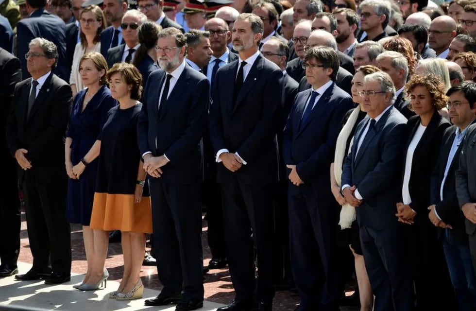Spain's King Felipe VI (5thL), Spanish Prime Minister Mariano Rajoy (4thL), President of Catalonia Carles Puigdemont (5thR) and officials observe a minute of silence for the victims of the Barcelona attack at Plaza de Catalunya on August 18, 2017, a day after a van ploughed into the crowd, killing 13 persons and injuring over 100 on the Rambla in Barcelona.\nDrivers have ploughed on August 17, 2017 into pedestrians in two quick-succession, separate attacks in Barcelona and another popular Spanish seaside city, leaving 13 people dead and injuring more than 100 others. In the first incident, which was claimed by the Islamic State group, a white van sped into a street packed full of tourists in central Barcelona on Thursday afternoon, knocking people out of the way and killing 13 in a scene of chaos and horror. Some eight hours later in Cambrils, a city 120 kilometres south of Barcelona, an Audi A3 car rammed into pedestrians, injuring six civilians -- one of them critical -- and a police