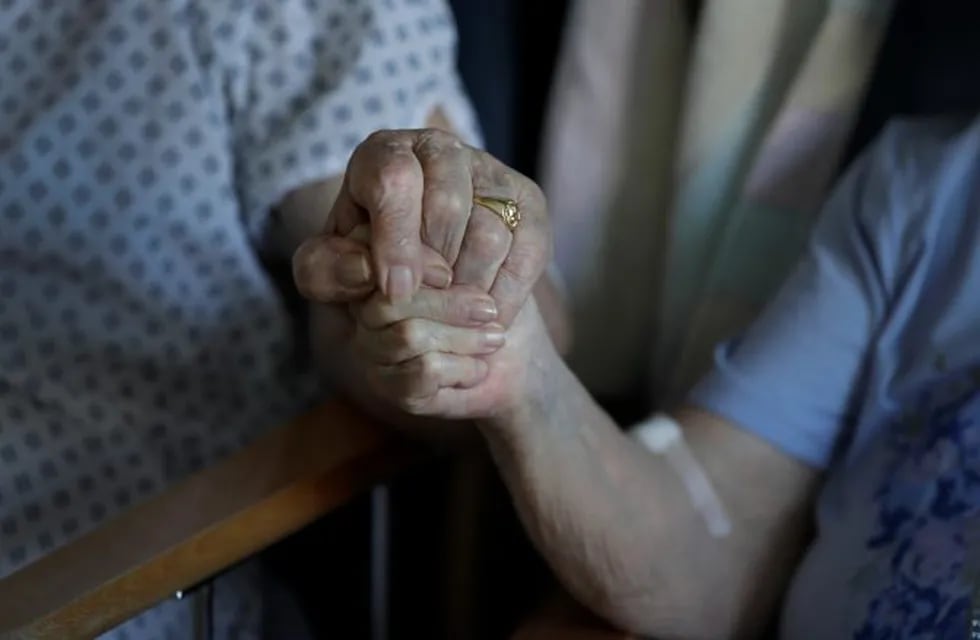 21 May 2020, England, Cambridge: Coronavirus (Covid-19) patients George Gilbert, 85 and his wife Domneva Gilbert 84, hold hands during a short visit, as they are being treated in different areas, as part of of the TACTIC-R trial, at the Addenbrooke's hospital in Cambridge. Photo: Kirsty Wigglesworth/PA Wire/dpa   manos abuelos mujer hombre jubilados geriatrico