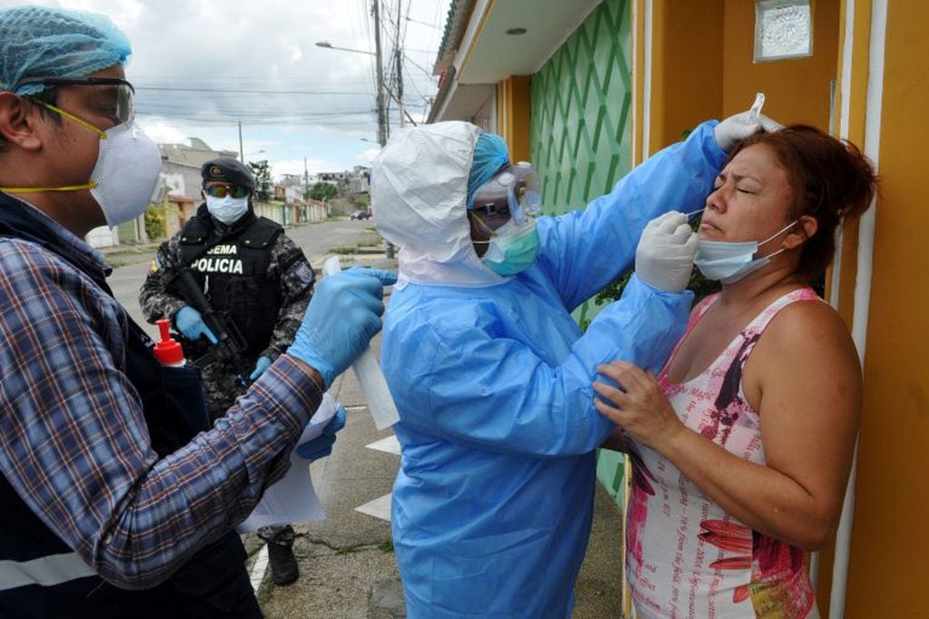 El personal del Ministerio de Salud examina a una mujer por COVID-19 en el complejo residencial Samanes 7 en el norte de Guayaquil, Ecuador, durante la pandemia de coronavirus. Guayaquil, la ciudad más grande de Ecuador, es la capital de la provincia de Guayas, donde se ha registrado aproximadamente 70 por ciento de los casos de coronavirus del país. (Photo by Jose SANCHEZ / AFP)