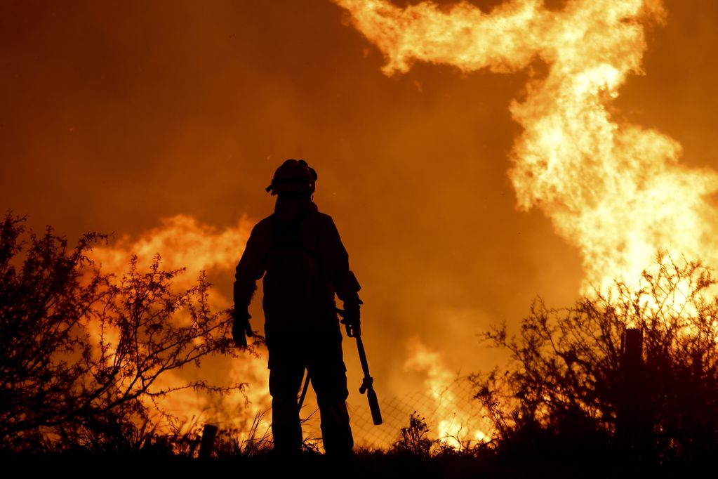 La silueta de un bombero contrasta con las llamas de un incendio forestal, el martes 10 de octubre de 2023, a las afueras de Villa Carlos Paz, Argentina. (AP Foto/Nicolas Aguilera)