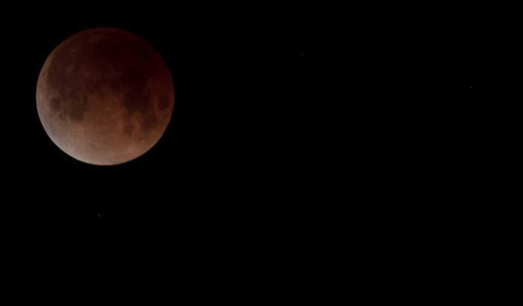 The eclipsing blood moon is shown in the early morning sky over North Vancouver, British Columbia, Canada,  Wednesday, Jan. 31, 2018.  It's the first time in 35 years a blue moon has synced up with a supermoon and a total lunar eclipse, or blood moon because of its red hue. Hawaii and Alaska had the best seats, along with the Canadian Yukon, Australia and Asia. The western U.S. also had good viewing, along with Russia. (Jonathan Hayward/The Canadian Press via AP)